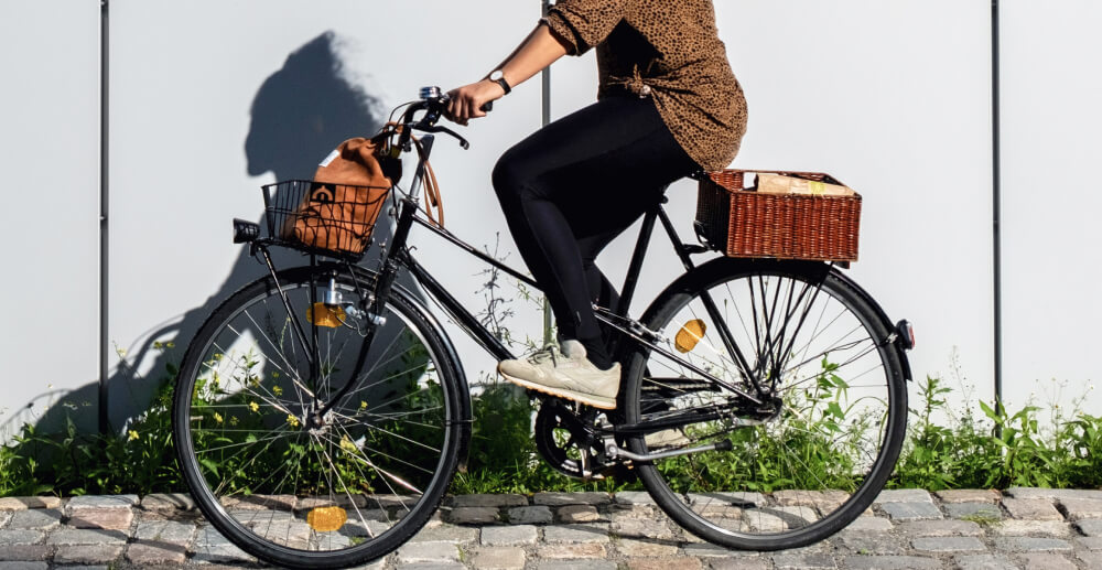 A woman rides a bicycle, her shadow cast on a nearby wall.