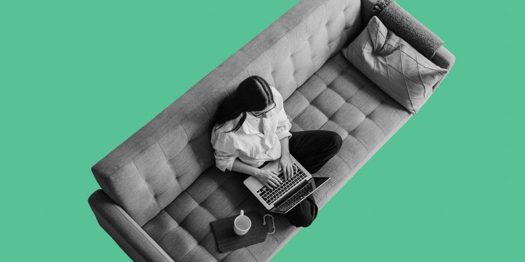 View from above of a woman on a sofa working on a laptop.