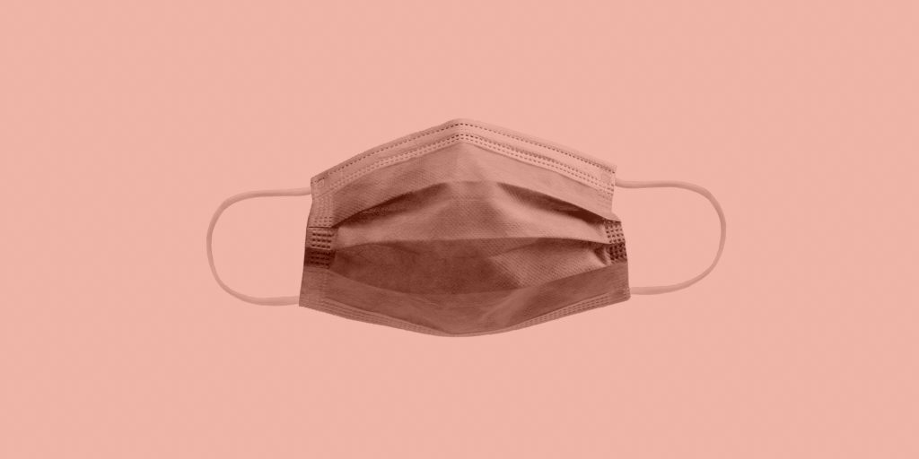 Disposable face mask on a peach background