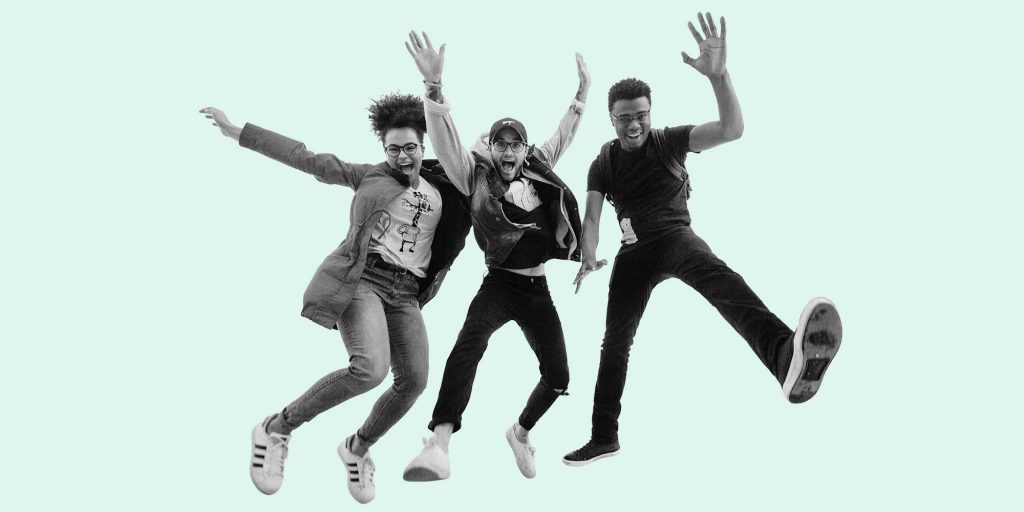 A trio of young adults jumping in the air and smiling. A new generation of recovery.