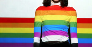 Woman in a rainbow sweater on a dark blue background. Being Open About My Bisexuality is a Huge Part of My Sobriety