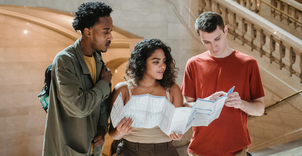 A ypung woman and two young men look at a paper map