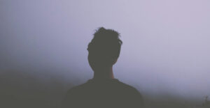 Silhouette of a woman looking away from the camera, into the fog.