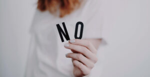 A woman in a white t-shirt holds out letters spelling NO.