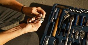 A person crouches over a toolbox that is open on the ground.