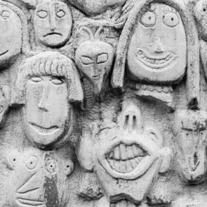 Bas relief of an eclectic mix of minimally detailed faces sculpted into a concrete wall. My recovery doesn't look like yours.