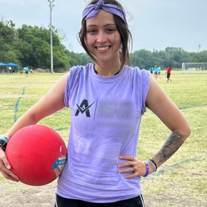 Destiny on a grassy sports field, holding a red dodge ball