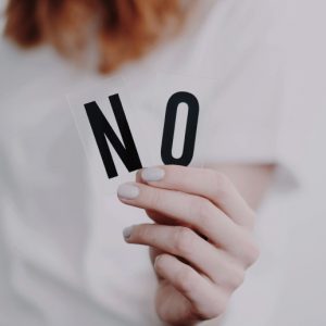 A woman in a white t-shirt holds out letters spelling NO.